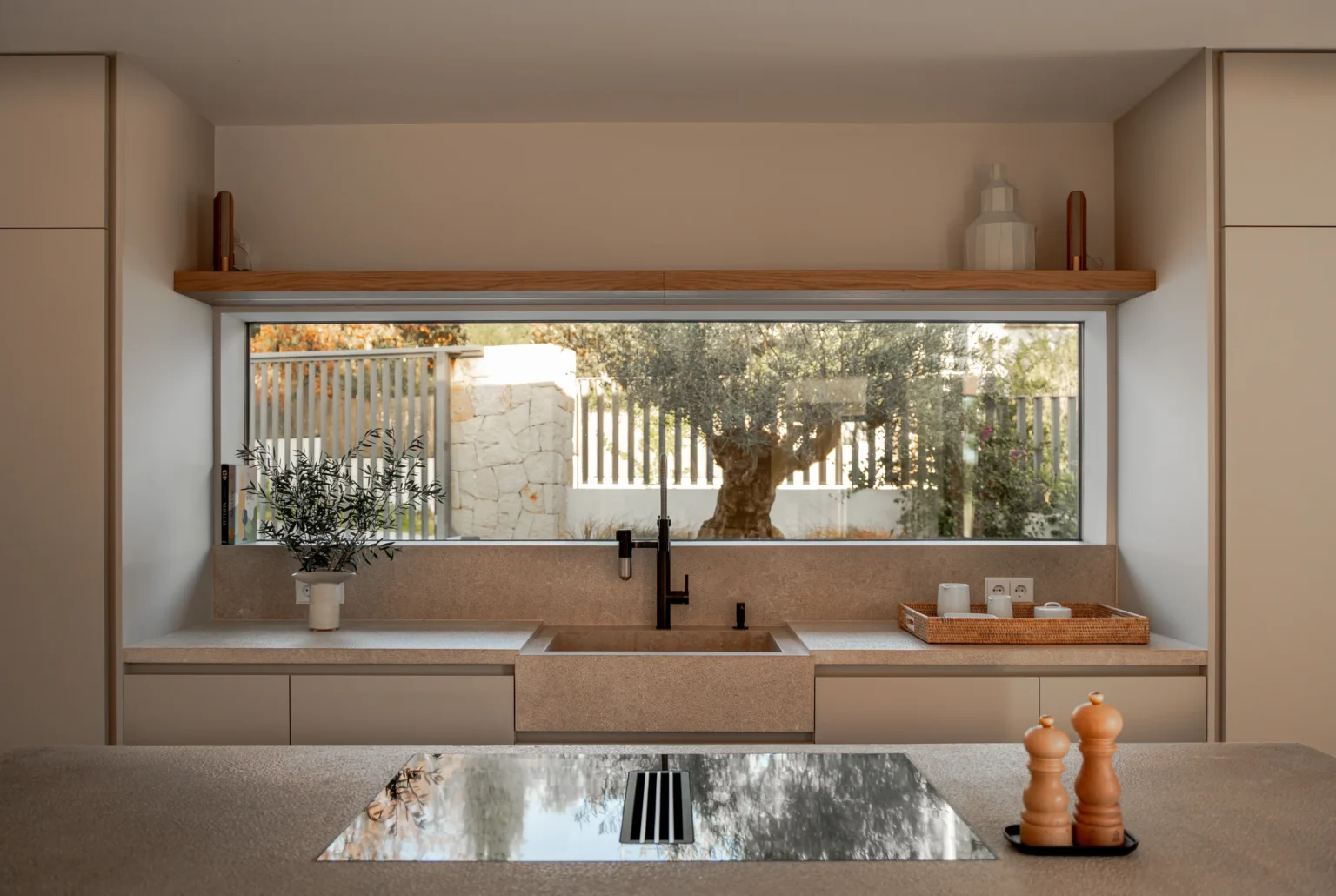 Fregadero con vistas al olivo desde la ventana de la cocina en el proyecto Pinar de Sa Dutxeta