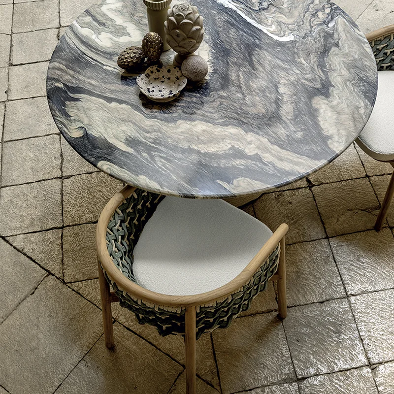 Detalle de mesa de exterior con tablero de piedra y silla trenzada de la colección Patio de Ethimo