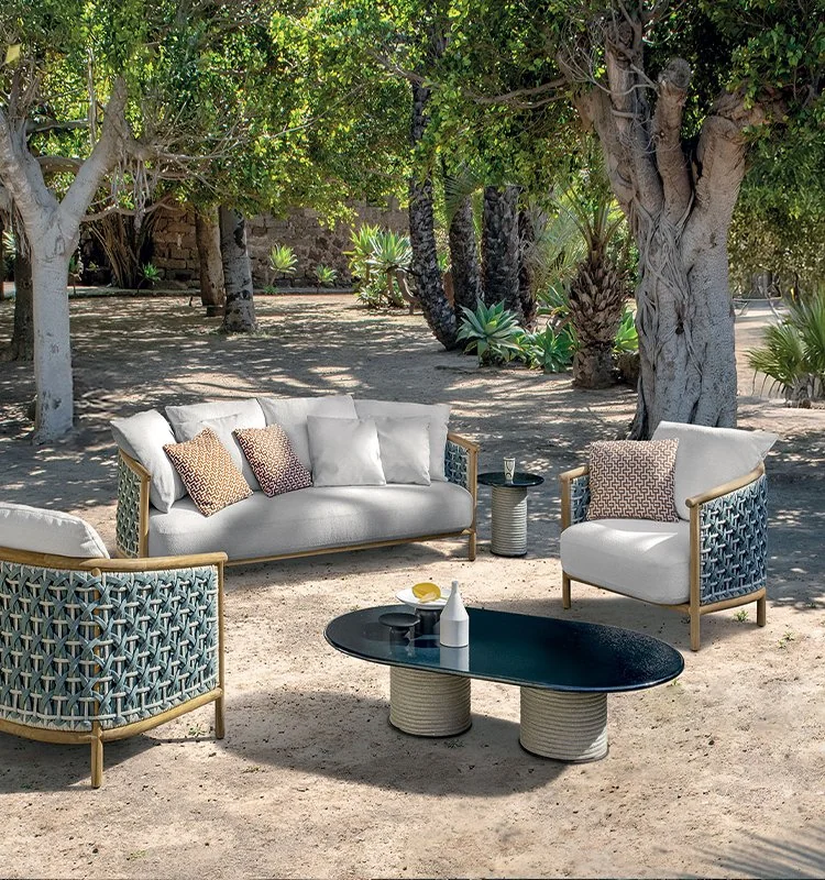 Salón de exterior bajo los olivos con sofá y butacas trenzadas de la colección Patio de Ethimo