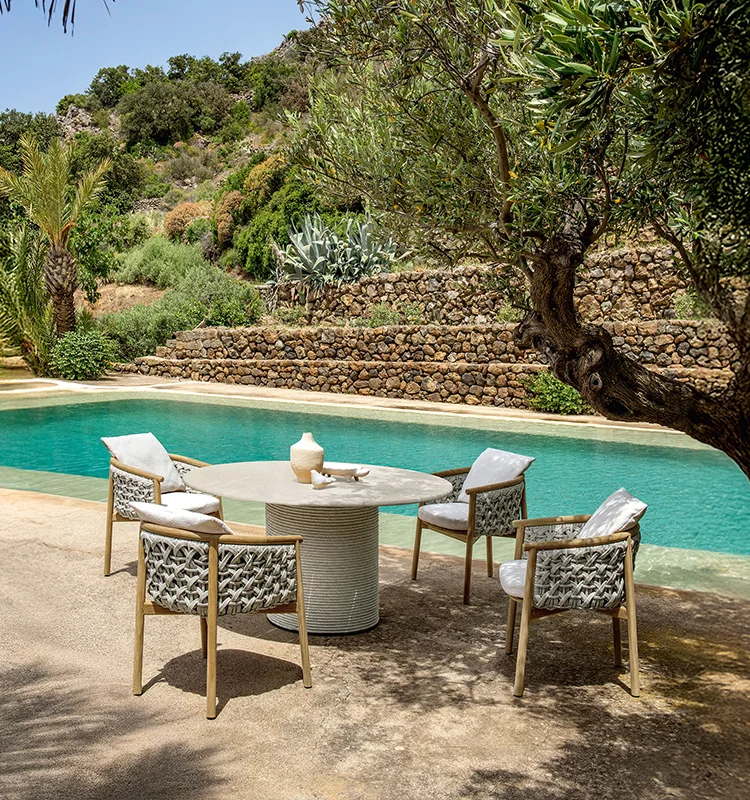 Comedor exterior junto a la piscina con mesa redonda y sillas de la colección Patio de Ethimo
