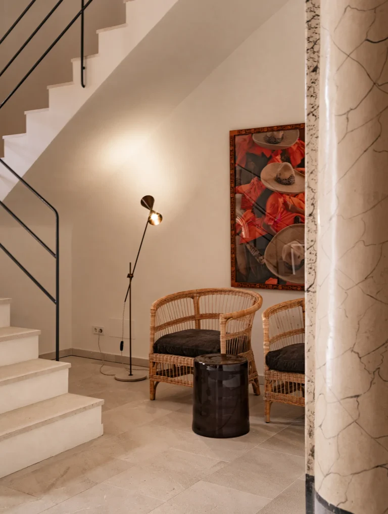 Escalera y rincón de lectura con butacas de ratán y cuadro en el proyecto 1906 de Sa Dutxeta en Sóller, Mallorca
